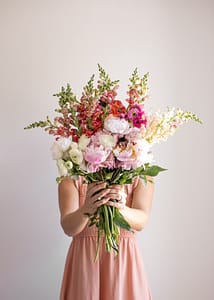 a woman holding flowers infront of her face