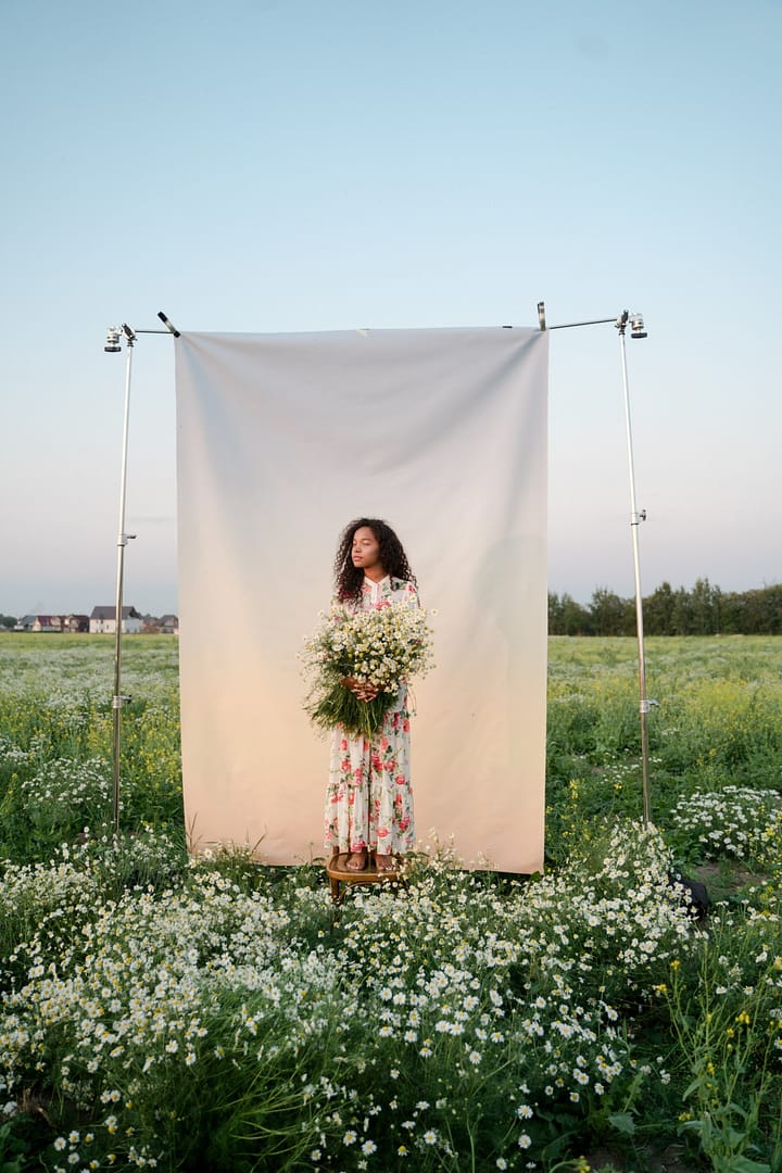 a woman holding flowers while standing on a chair in a field full of flowers